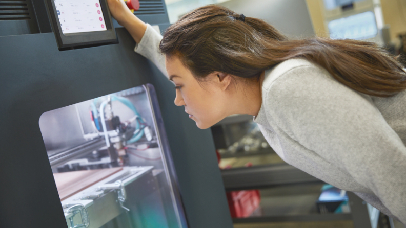 a woman looking into a 3D printer